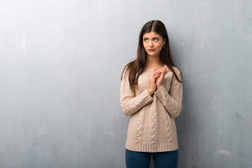 Teenager girl with sweater on a vintage wall scheming something