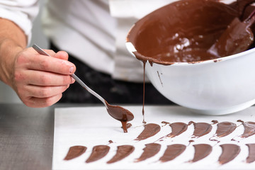 Professional confectioner making chocolate sweets at confectionery shop .