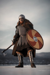Medieval Scandinavian warrior Viking in full outfit on shore of winter sea