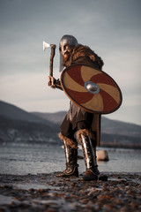 Medieval Scandinavian warrior Viking in full outfit on shore of winter sea