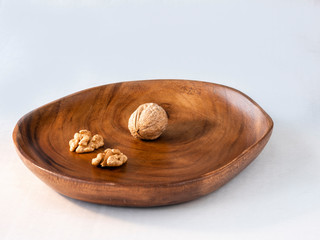 One nut and two halves of the nut on the wooden plate and white background
