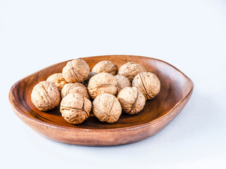 Some nuts on the wooden plate and white background