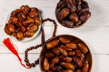 Dates fruit and rosary on white wooden table. Top view