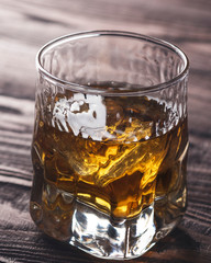 Whiskey with ice in  a glass  on rustic wood background. Closeup