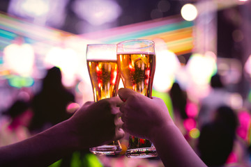 Beer glasses raised in a toast. people enjoy the party with drinking beer in the nightclub.