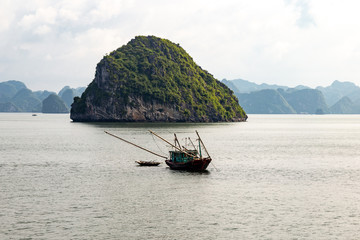 A local fisherman boat among the karst formations in Halong Bay, Vietnam, in the gulf of Tonkin. Halong Bay is a UNESCO World Heritage Site and the most popular tourist spot in Vietnam