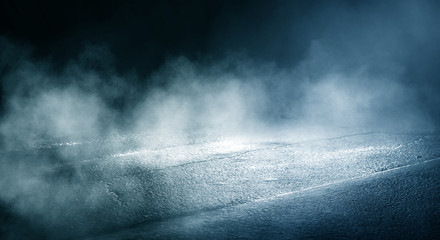 Black background of empty street, room, blue searchlight illuminates asphalt, smoke