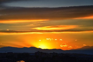 Tranquil panoramia scene of red sun and orange sky sunset over the Rocky Mountains in Colorado by Denver, United States.