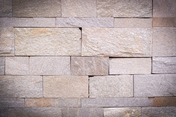 Obraz premium beige weathered stone tiled wall background with vignette. texture.