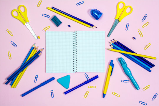 Set of multicolored office supplies on a pink background.