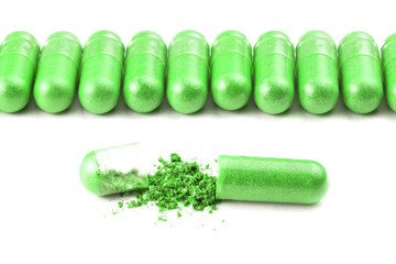 row of ufo green color organic capsules isolated on white background closeup with one opened