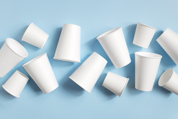 White disposable cups on the light blue background - obrazy, fototapety, plakaty