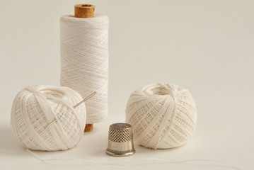 Fototapeta na wymiar spools with white threads, needle and thimble on white background close-up.