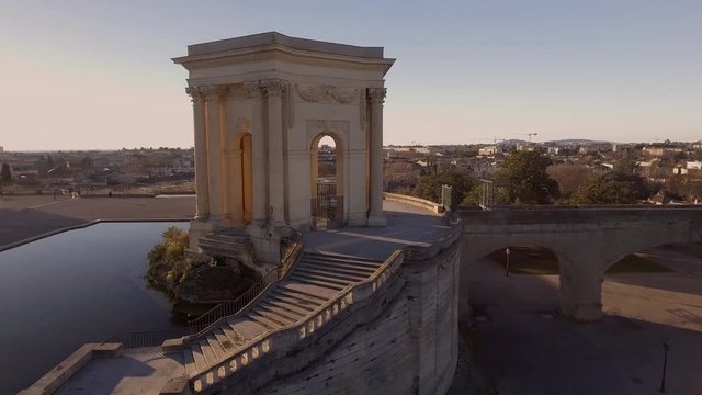 Beautiful sunlight flare flying over water tower in Montpellier Peyrou parc aerial drone shot