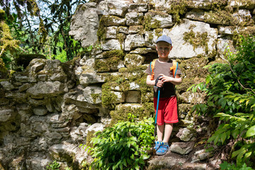 Naklejka na ściany i meble Boy traveler stands near the ruins of ancient walls
