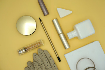Flat lay composition of beauty products and handbag for women. Pastel and gold colors on gold background. Top view.