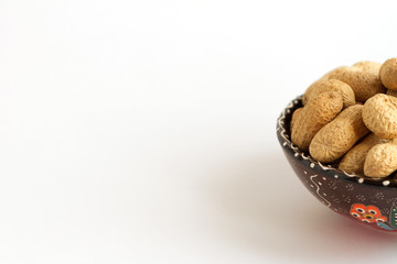 Raw peanuts in shell on cup on white background. Copy space for text