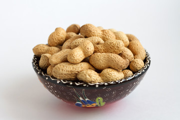 raw peanuts in shell on clay cup on white background