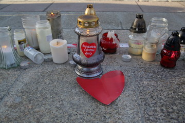 Zapalone znicze, świece, słynne czerwone serduszko z napisem The Great Orchestra of Christmas Charity, czerwone serce z papieru, na ziemi © Wioletta