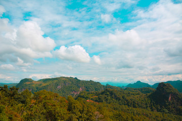 green forest in aerial view. Landscape of village in the valley and beautiful blue sky with fluffy white clouds