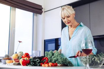 Nice aged woman cutting fresh green lettuce