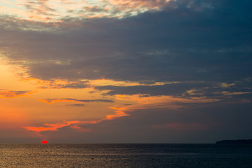Amazing sea sunset on the pebble beach, the sun, waves, clouds