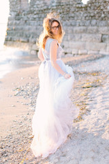 Fototapeta na wymiar young beautiful woman in blue elegant dress walking near the lake Garda and fortress in Sirmione, Italy. Lovely walk in Sirmione