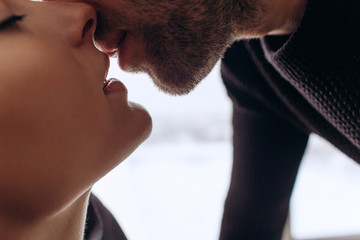 Close-up of young romantic couple is kissing and enjoying the company of each other at home.