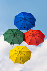 4 fliegende Regenschirme in den Farben rot gr&uuml;n blau und gelb