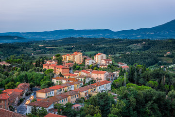 Naklejka na ściany i meble Chiusi village cityscape before sunrise in Umbria Italy with illuminated hdr lights on streets and rooftop houses on mountain countryside and rolling hills