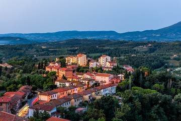 Fototapeta na wymiar Chiusi village in morning before sunrise in Umbria Italy with illuminated lights on streets and rooftop houses on mountain countryside and rolling hills