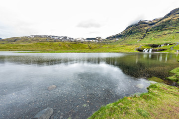 Grundarfjordur, Iceland wide angle landscape view of Kirkjufell waterfall landmark with clear transparent water in green cloudy day