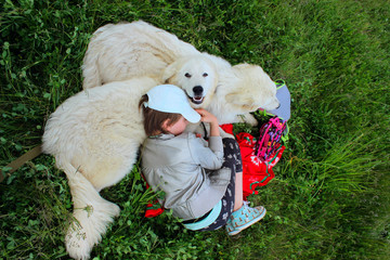 Cute Young Girl Paying With Her Pets. Girl And Two White Dog Outdoors. People, Travel, Pets, Childhood Concept.

