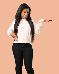 Young afro american woman holding copyspace imaginary on the palm to insert an ad on isolated brown background