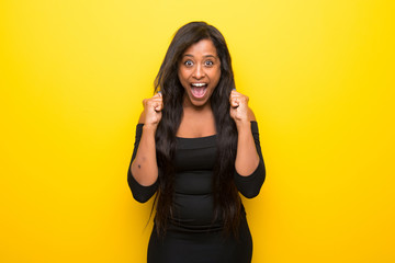 Young afro american woman on vibrant yellow background celebrating a victory in winner position