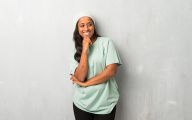 Young afro american woman on textured background looking to the side with the hand on the chin