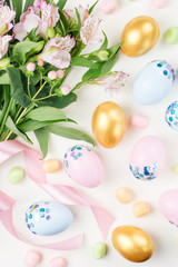 Festive Easter background with decorated eggs, flowers, candy and ribbons in pastel colors on white. Copy space