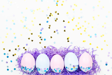 Festive Easter background with decorated eggs, flowers, candy and ribbons in pastel colors on white. Copy space