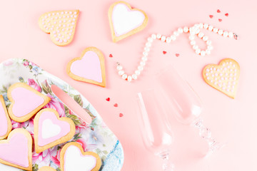 Happy Valentine's day greeting card with heart cookies, wine glasses and wine on pastel pink background.