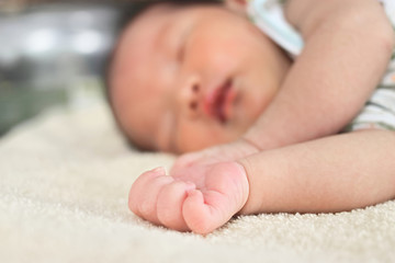 Selective focus on hands of cute newborn tiny Asian baby