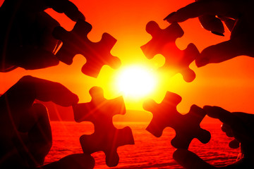 puzzles in the hands of people on the background of the evening sky. logic, interaction,...