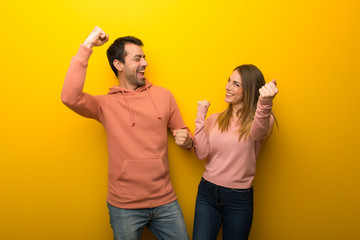 Group of two people on yellow background celebrating a victory in winner position