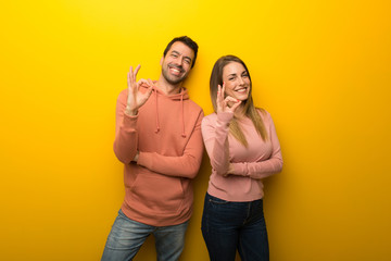 Fototapeta premium Group of two people on yellow background showing an ok sign with fingers