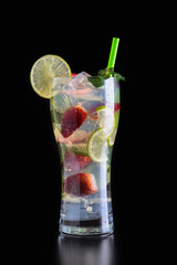 Freshly made refreshing mojito in a tall glass with strawberry, lime, fragrant mint leaves and ice on a dark table and background