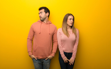 Group of two people on yellow background is a little bit nervous and scared pressing the teeth