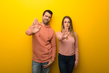 Fototapeta premium Group of two people on yellow background making stop gesture denying a situation that thinks wrong