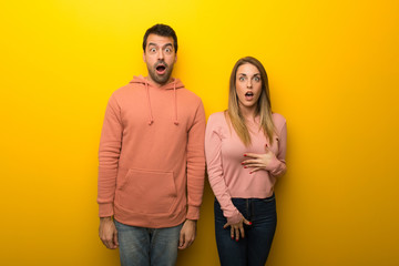 Group of two people on yellow background with surprise and shocked facial expression