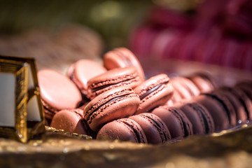 Display of pile of gourmet colorful pink red velvet chocolate macaroons macarons on shelf in bakery store shop
