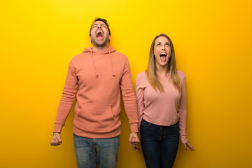 Group of two people on yellow background shouting to the front with mouth wide open