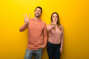 Fototapeta premium Group of two people on yellow background happy and counting three with fingers